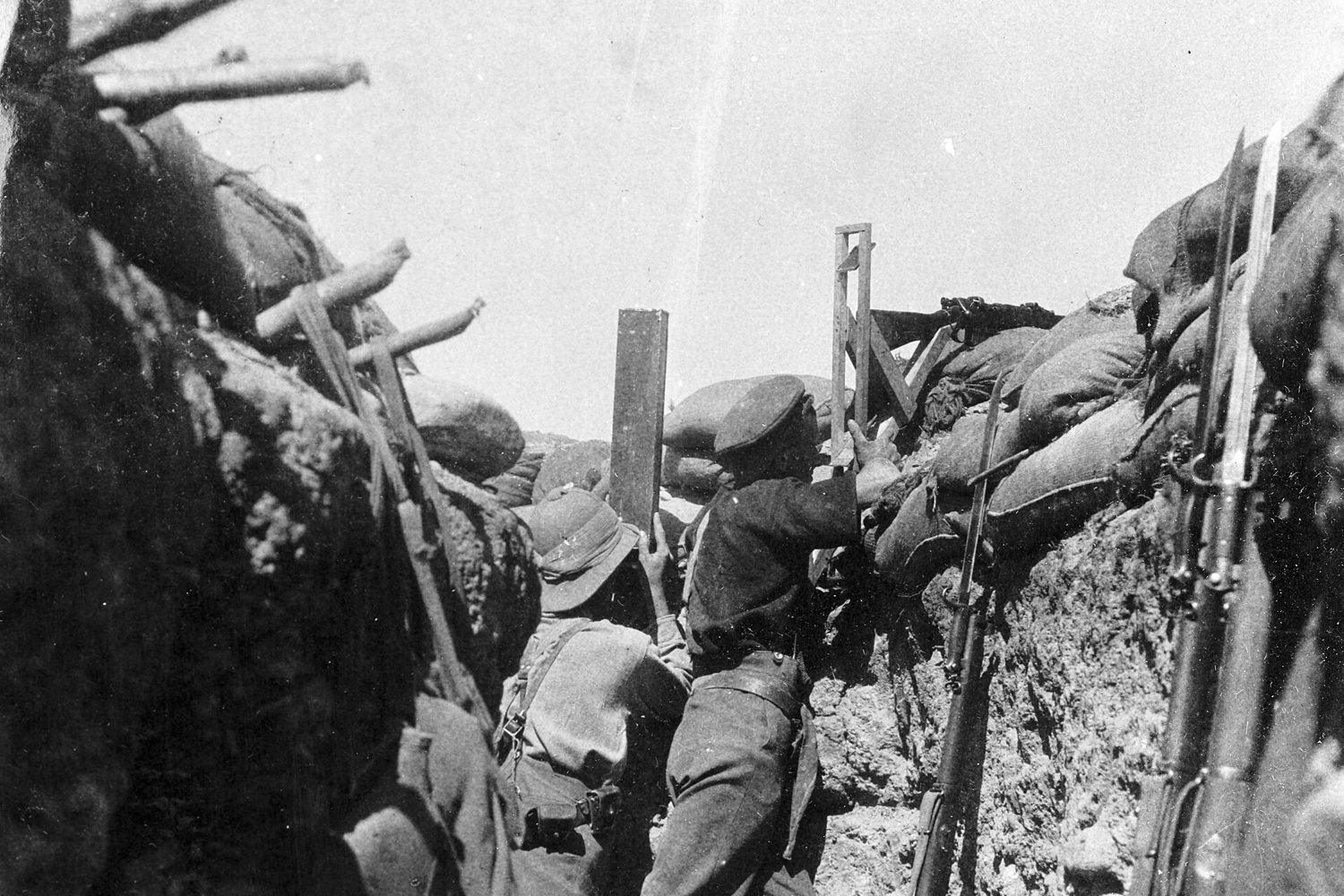 A soldier firing a periscope rifle over the sandbags of a trench at Gallipoli, 1915